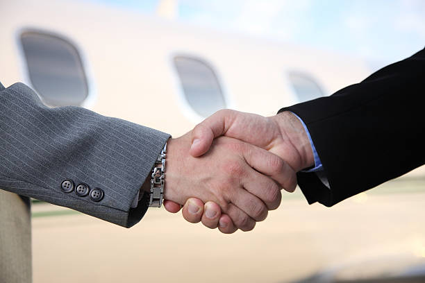Closeup of businessmen shaking hands in front of a corporate jet